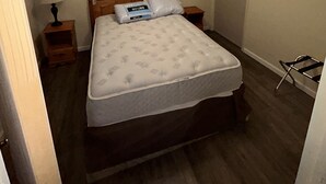A bedroom with a wooden bed, a nightstand with a lamp, a ceiling fan, and a door. - Spacious 2 Bedroom Apartment downtown Winifred,8 miles from the Missouri Breaks! (Winifred)