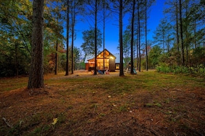 A cabin surrounded by tall trees, with a clear view of the surrounding forest. - Chillax Inn · Tranquil Getaway: Pet-Friendly, Hot Tub & Foosball (Broken Bow)