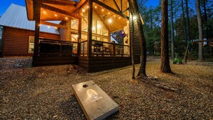 Een houten blokhut met een overdekte veranda, een eethoek en uitzicht op het omliggende bos.