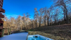 Un jacuzzi con terraza de madera y vistas a un área boscosa.