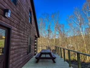 Una cabaña de madera con un balcón y una mesa de picnic.