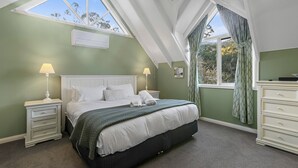 Une chambre à coucher comprenant un lit, deux tables de chevet, une commode, une fenêtre avec des rideaux et un puits de lumière.