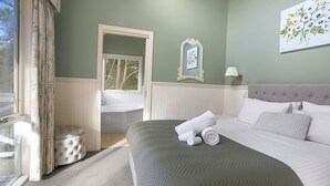 Ein Schlafzimmer mit Bett, Fenster, Bad und einem Bild an der Wand.
