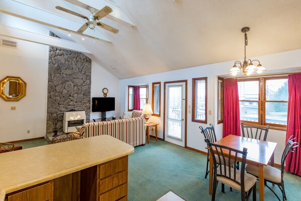 A spacious kitchen with a stone accent wall, a dining area with wooden chairs, and a ceiling fan.