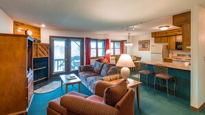 Un espacio habitable compacto con sofá, sillas, una mesa de comedor, una zona de cocina y una chimenea.