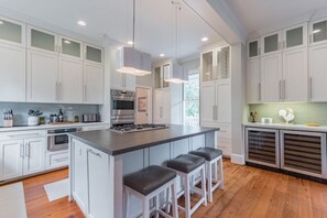 A spacious kitchen with white cabinets, a central island with stools, stainless steel appliances, and pendant lighting. - Charleston Home-Walk to 5pts/USC (Columbia)