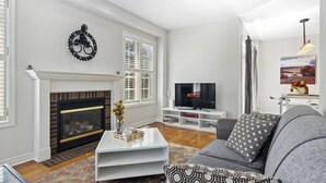A living room with a fireplace, a television, a sofa, and a coffee table. - The cozy corner house in the Richmond Hill  (Richmond Hill)