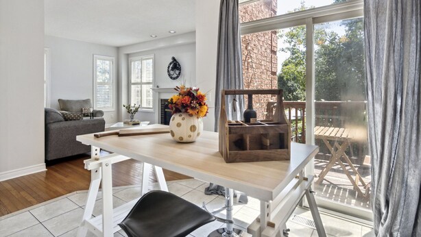 A modern living room with a wooden dining table, a black chair, and a vase with flowers. - The cozy corner house in the Richmond Hill  (Richmond Hill)