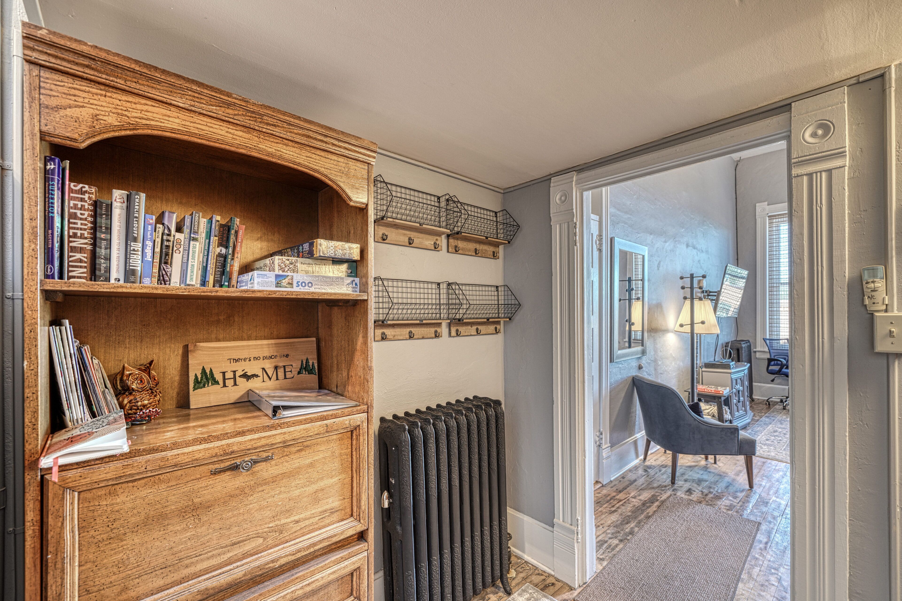 A room with a wooden bookshelf, a radiator, and a chair.