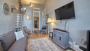 A living room with a sofa, a television, a cabinet, and a staircase leading to another room. - A Charming Loft in Downtown Salida! (Salida)