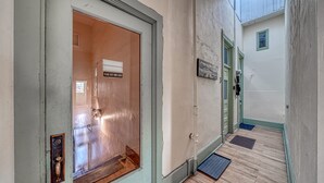 A hallway with a closed door, a doormat, a small mat, and a wall-mounted picture. - A Charming Loft in Downtown Salida! (Salida)