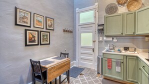 A dining area with a wooden table and chairs, a kitchen with green cabinets, and a door with a white frame. - A Charming Loft in Downtown Salida! (Salida)