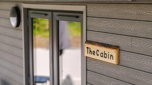 A wooden sign with "The Cabin" written on it, attached to a building with horizontal siding. - The Cabin in the Tamar Valley Cornwall (Gunnislake)