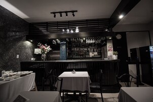 Un restaurante con zona de bar, paredes de mármol y un reloj en la pared.