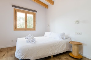 A bedroom with a bed, a window, a wall socket, and a cat tree.