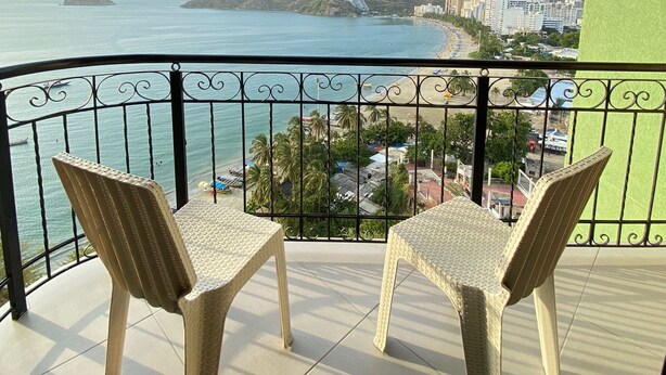 Un balcon avec deux fauteuils en osier donnant sur la mer.