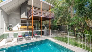 Une maison moderne dotée d’une piscine, d’un espace salon extérieur et d’un patio couvert.