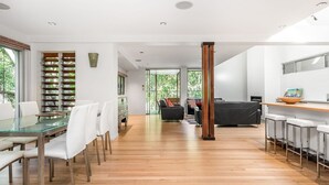 Une cuisine moderne avec un coin repas, un plancher en bois et de grandes fenêtres.