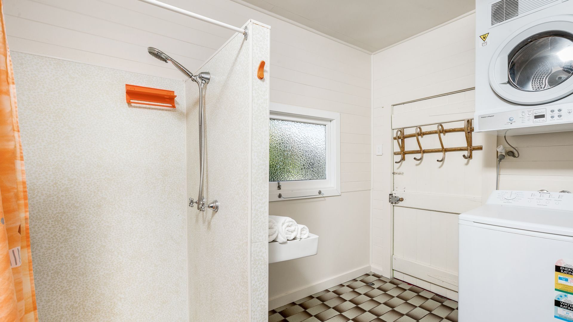 A laundry room with a washing machine, a dryer, and a shower.