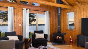 A cozy cabin with a fireplace, wooden walls, and a view of a lake. - ~Fireworks On The 3rd~Sunrise Vista~Lakefront~Dock~Kayaks~Hot Tub~Games~NEW AC~ (Gaylord)