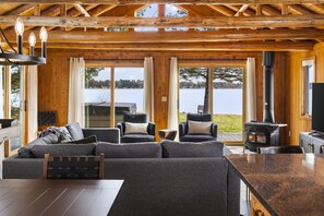 A cozy cabin interior with a large sofa, two armchairs, a dining table, and a wood-burning stove. - ~Fireworks On The 3rd~Sunrise Vista~Lakefront~Dock~Kayaks~Hot Tub~Games~NEW AC~ (Gaylord)