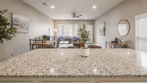 A spacious kitchen with granite countertops, a central island, and a ceiling fan. - Newly renovated 4BR CozySuites (Louisville)