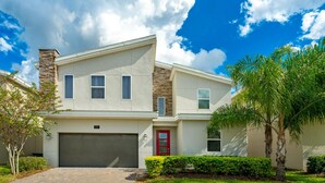 A modern two-story house with a garage, a red door, and a stone chimney. - New - Sleeps 21 - Champions Gate Hyperdrive House (Kissimmee)