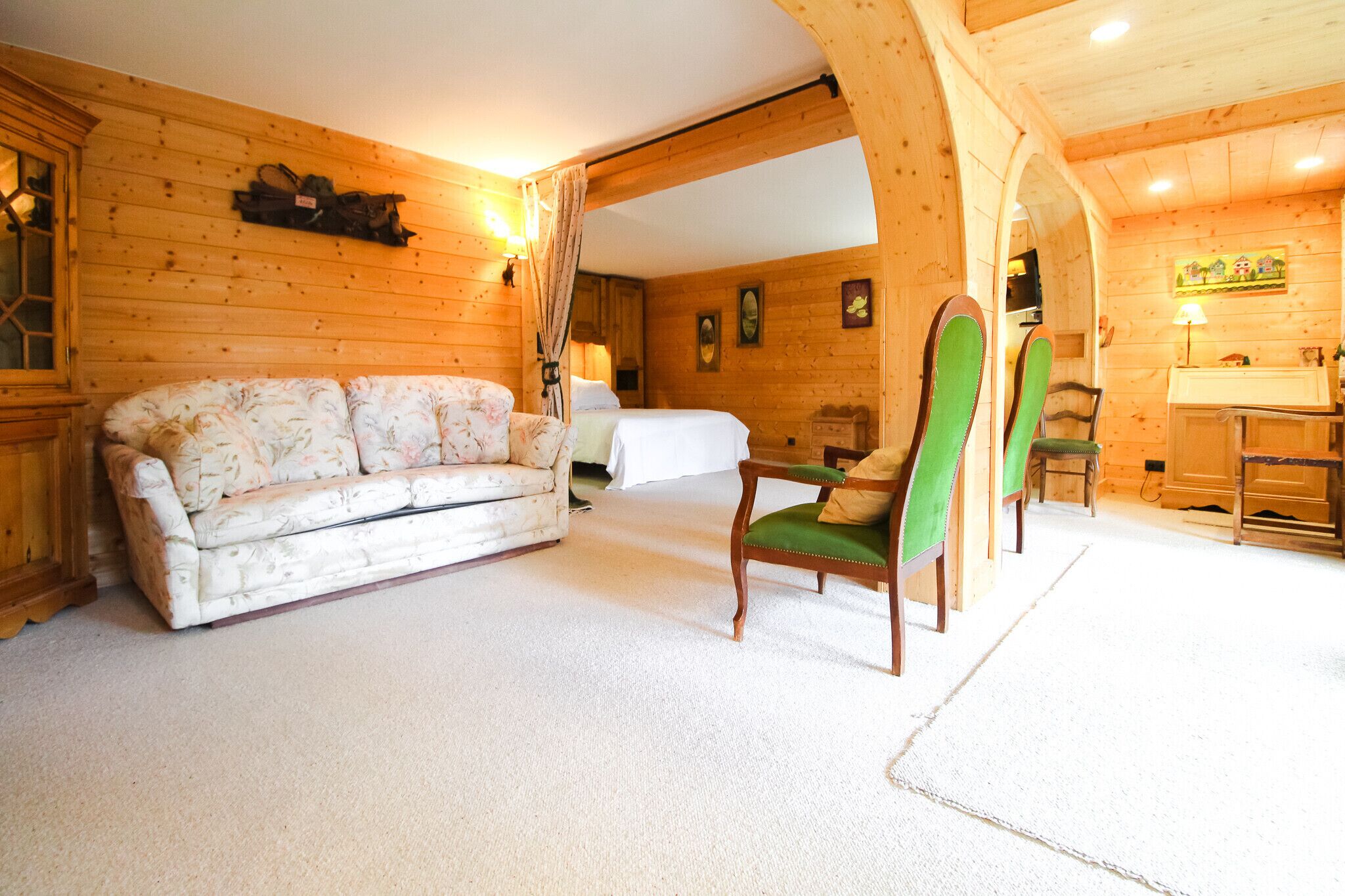 A wooden interior with a sofa, a chair, and a bed.