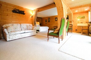 Un interior de madera con sofá, sillón, cama y una mesita.