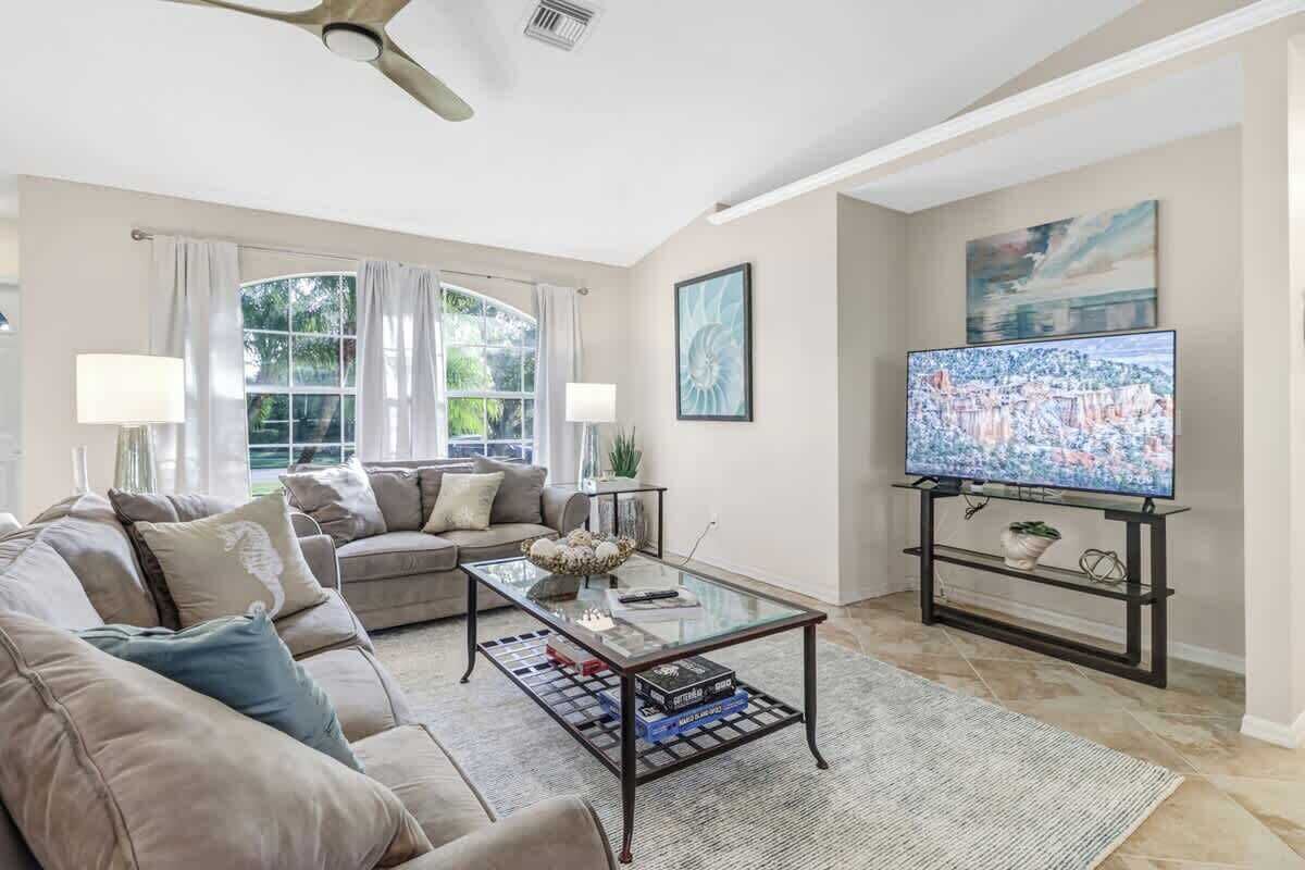 A living room with a sofa, coffee table, TV, and artwork.