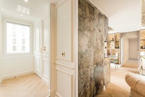 A spacious room with a large window, a marble accent wall, and a cozy seating area.