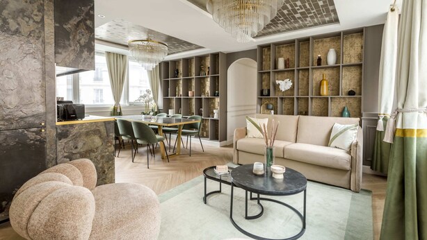 Een moderne woonkamer met een bank, stoelen, een salontafel en een boekenkast.