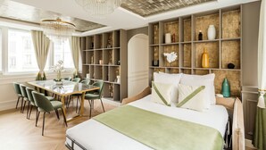 Een moderne hotelkamer met een groot bed, een zithoek met een marmeren tafel, en een decoratieve wand met planken.