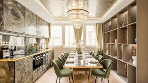 Een moderne eetkamer met een marmeren keuken, een kroonluchter en een boekenkast.