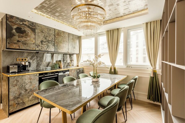 A modern kitchen with a marble countertop, green chairs, and a central island.