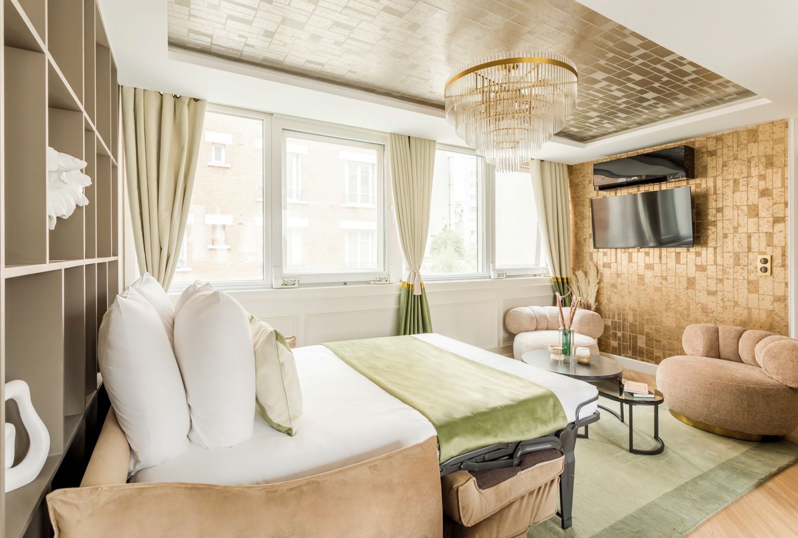 A modern hotel room with a bed, a sofa, a TV, and a view of the city.