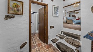Um corredor com porta de madeira, degraus de pedra e chão de azulejos.