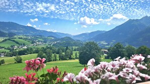 A mountainous landscape with a village, green fields, and a clear sky.