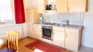 A kitchen with wooden cabinets, a microwave, a stove, and a sink.