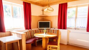 A cozy room with a wooden table, a television, and a bench.