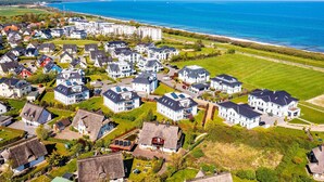 An aerial view of a residential area with houses, a beach, and a clear sky. - Apartment 'Waterkant 2-50' with Sea View, Balcony and Wi-Fi (Börgerende-Rethwisch)