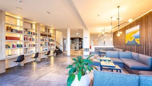 A modern library with bookshelves, seating areas, and a large plant. - Apartment 'Waterkant 2-50' with Sea View, Balcony and Wi-Fi (Börgerende-Rethwisch)