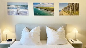A hotel room with a bed, two nightstands, a lamp, a remote control, and three framed pictures on the wall. - Apartment 'Villa Deichgraf 07 Ostseeblick' with Sea View, Balcony and Wi-Fi (Börgerende-Rethwisch)