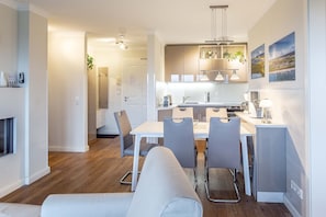 Une cuisine moderne avec un coin repas, un plancher en bois et des luminaires suspendus.