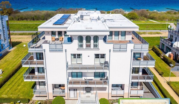 Un hôtel à plusieurs étages doté de balcons, de panneaux solaires et offrant une vue sur l’océan.