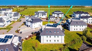 A residential area with houses, solar panels, and a view of the sea. - Apartment 'Dünenrose 04 Wolkenlos' with Sea View, Balcony and Wi-Fi (Börgerende-Rethwisch)