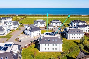 Un quartier résidentiel avec des maisons, des panneaux solaires et une vue sur la mer.