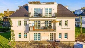 A two-story building with a balcony, a sign reading 'Dünenrose,' and a number '29' on the ground floor. - Apartment 'Dünenrose 04 Wolkenlos' with Sea View, Balcony and Wi-Fi (Börgerende-Rethwisch)