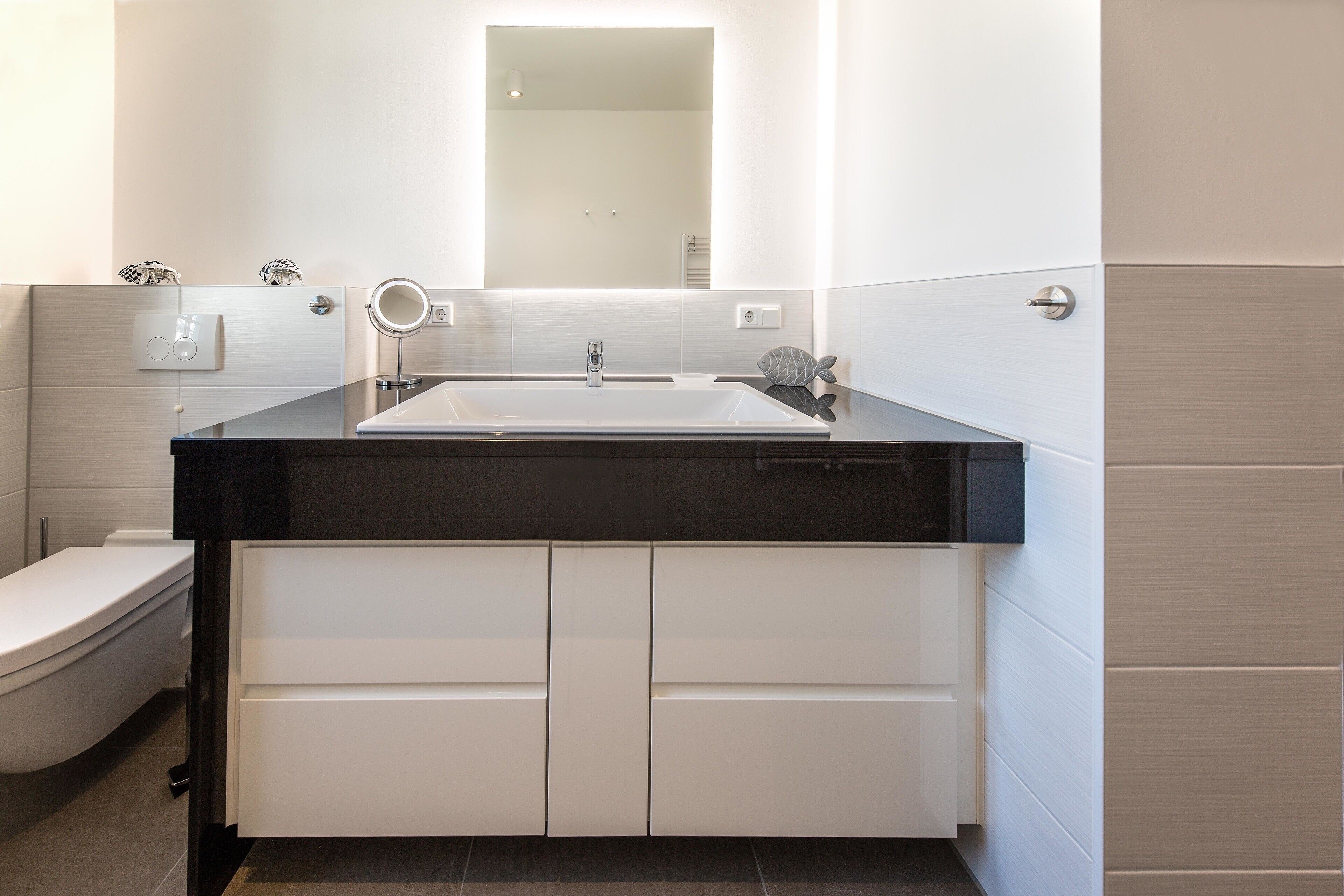 A bathroom with a white sink, a mirror, and a toilet.