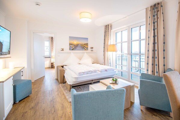 Une chambre d’hôtel équipée d’un lit, d’un bureau, d’une chaise, d’un canapé, d’une télévision et d’une fenêtre avec des rideaux.